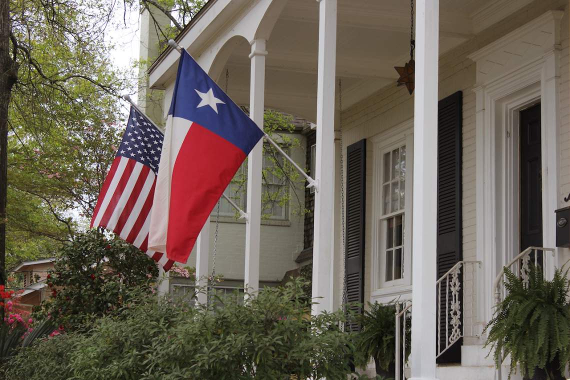 Historic Home With Texas and American Flags Springtime
